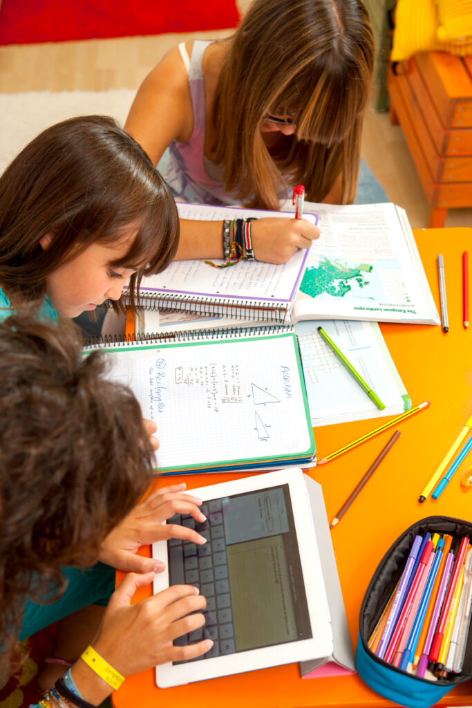 Three teenage girls busy with homework at desk